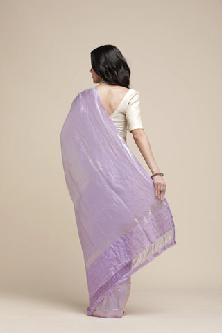 Woman wearing a light purple saree with a subtle pattern on a beige background