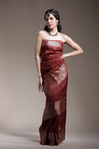 Woman wearing a strapless burgundy dress against a plain background