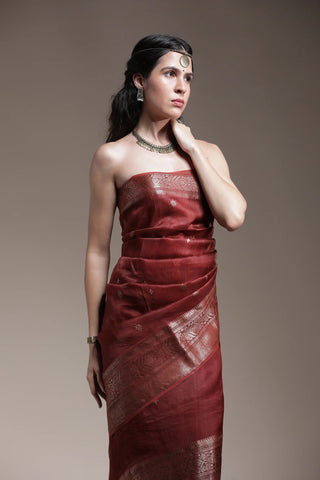 Woman wearing a red dress with intricate patterns against a plain background