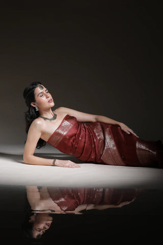 Woman in a red dress lying on a reflective surface with a dark background