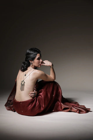 Woman in a red dress sitting on a gray floor with a dark background