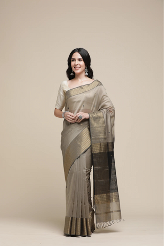 Woman wearing a traditional saree against a plain background