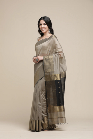 Woman wearing a traditional saree with a beige and black pattern on a plain background