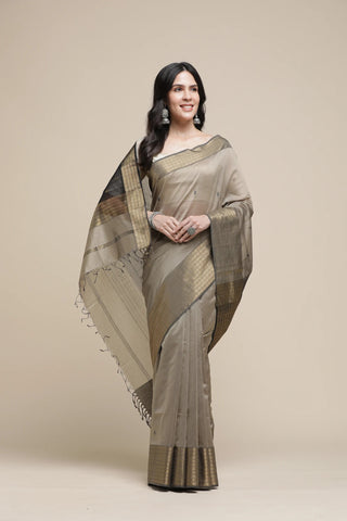 Woman wearing a traditional saree with a beige and brown color scheme on a plain background