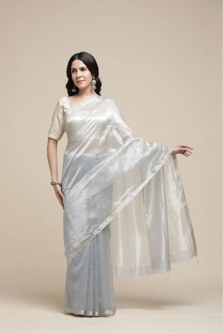 Woman wearing a silver saree with a plain background