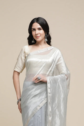 Woman wearing a light gray saree with a plain background