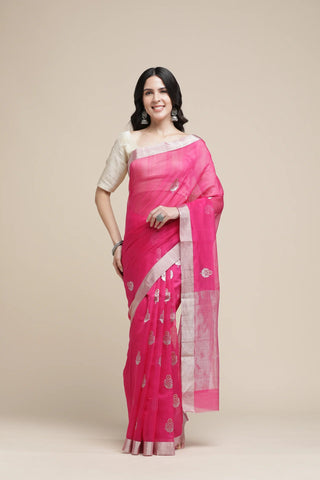 Woman wearing a pink saree with a white blouse on a beige background
