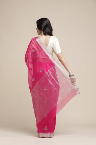 Woman wearing a pink and white saree with a plain background