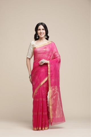 Woman wearing a pink saree with a gold border on a beige background