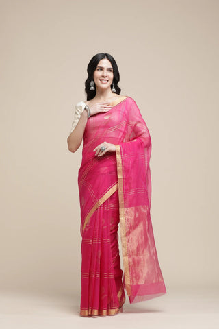 Woman wearing a pink saree with a gold border on a beige background
