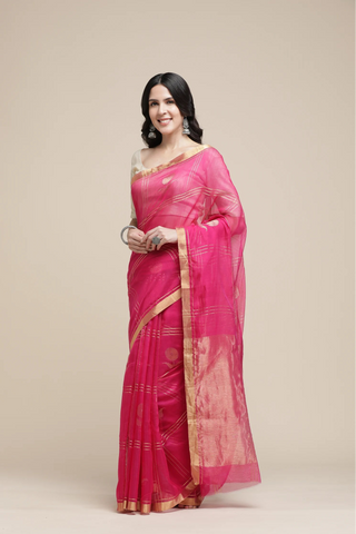 Woman wearing a pink saree with gold border on a beige background