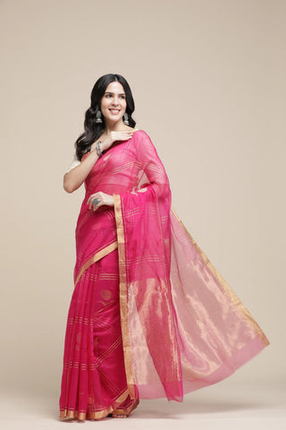 Woman wearing a pink saree with a gold border on a beige background