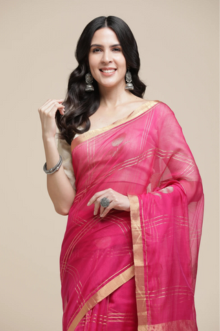 Woman wearing a bright pink saree with a beige background