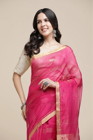 Woman wearing a pink saree with a beige blouse on a beige background