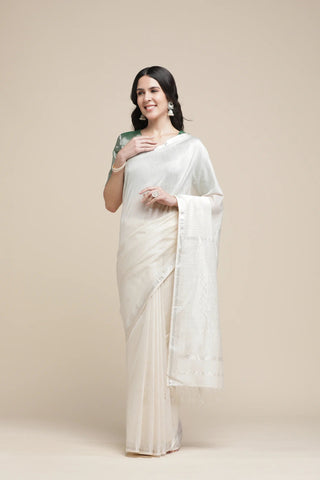 Woman wearing a white saree with a plain background