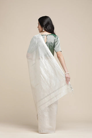 Woman wearing a light green saree with a plain background