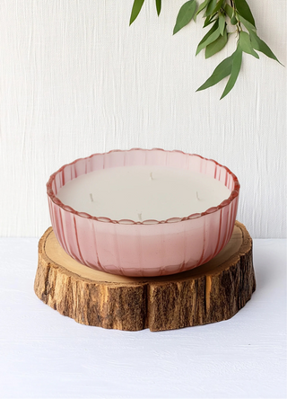 Pink glass bowl on a wooden stand with a white background