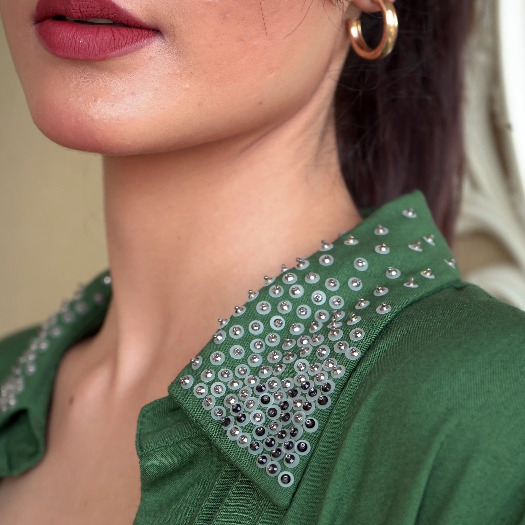 Close-up of a person wearing a green garment with embellished collar.