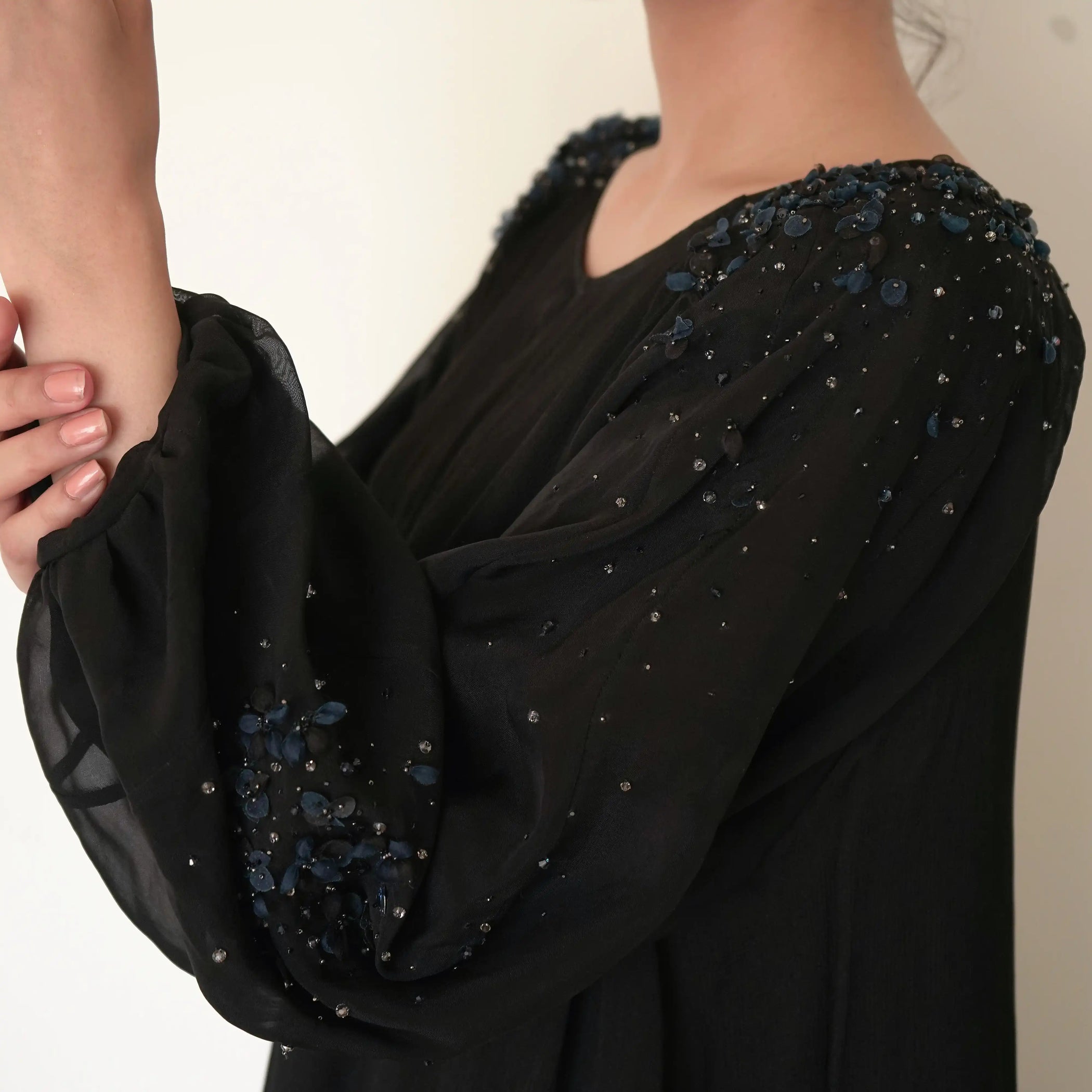 Black garment with decorative elements on a neutral background