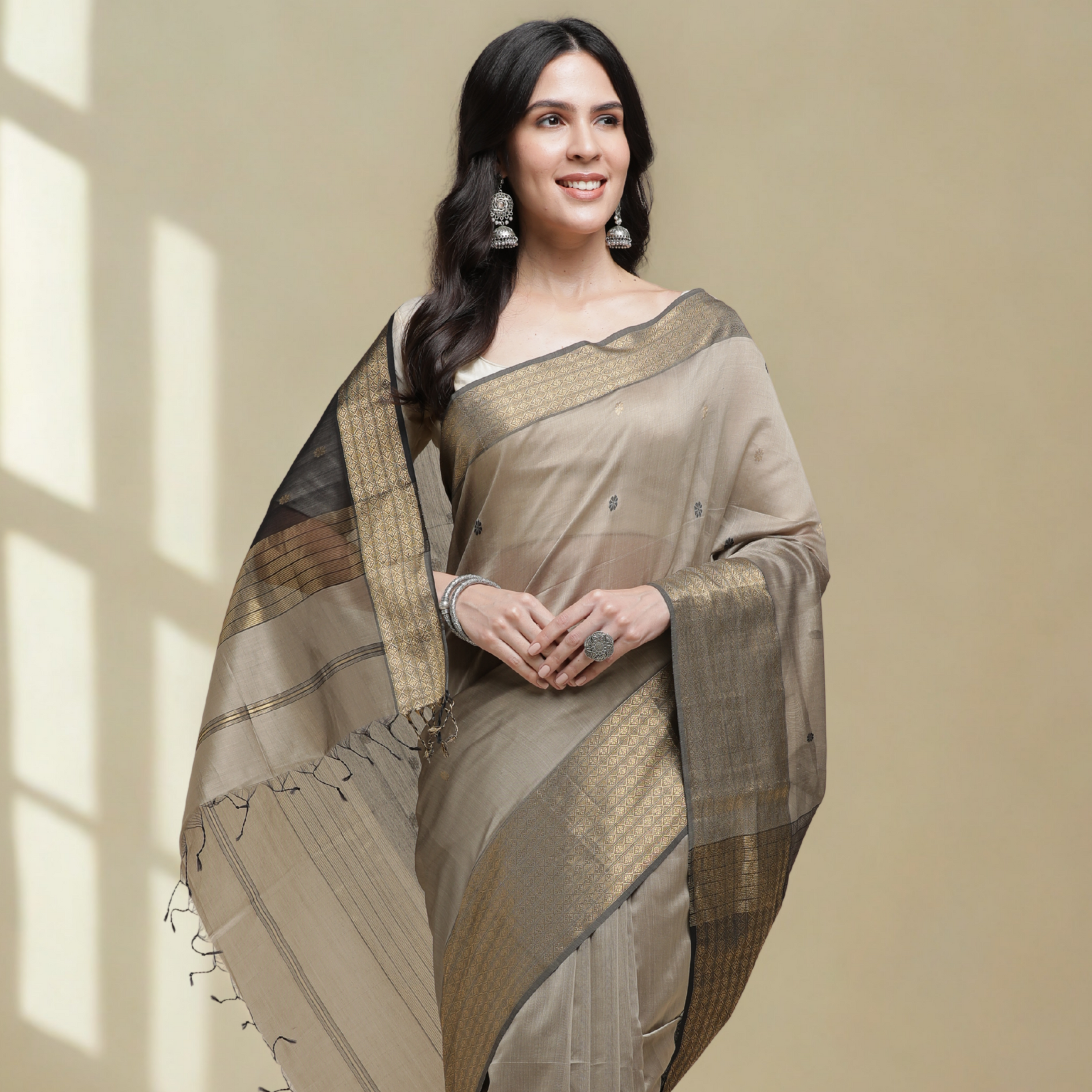 Woman wearing a traditional saree against a beige background